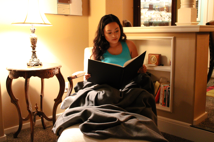 Woman reading book while covered up with the TrueLight Luna Red IR+FIR Blanket for rejuvenation