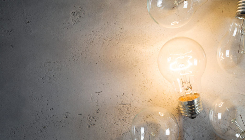 Light bulbs on concrete with one illuminated