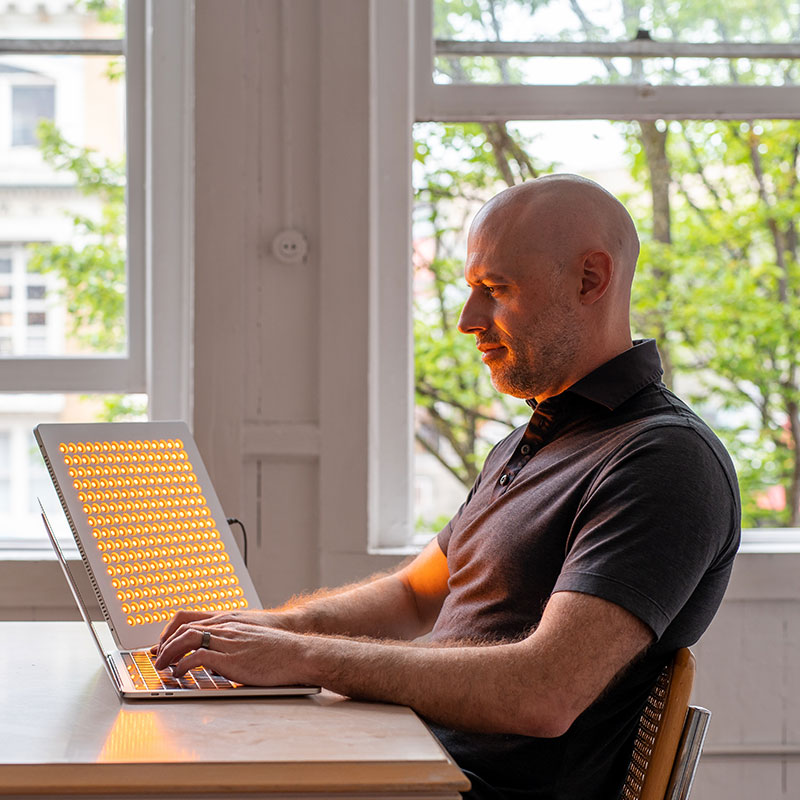 Middle aged man using the TrueLight® Energy Square 2.4 for yellow light therapy
